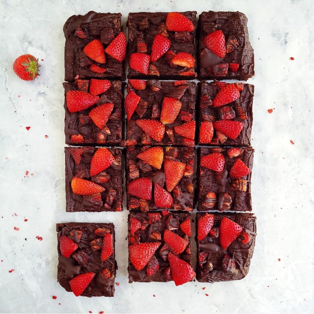functional image strawberry brownies drizzled with chocolate and cut into 12 squares. top down view with fresh strawberries on top