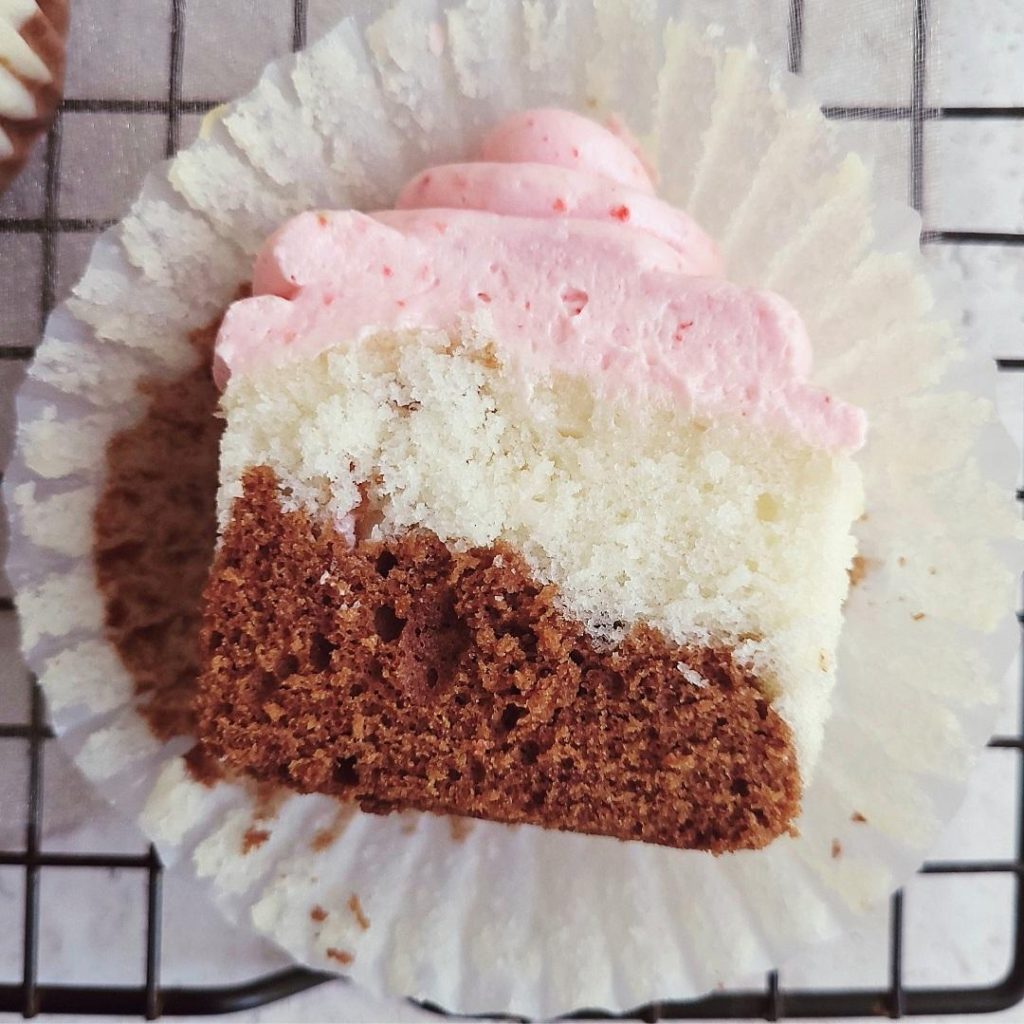 functional image neapolitan cupcakes top down view of a single cupcake sliced in half to see the chocolate and vanilla crumb with strawberry frosting