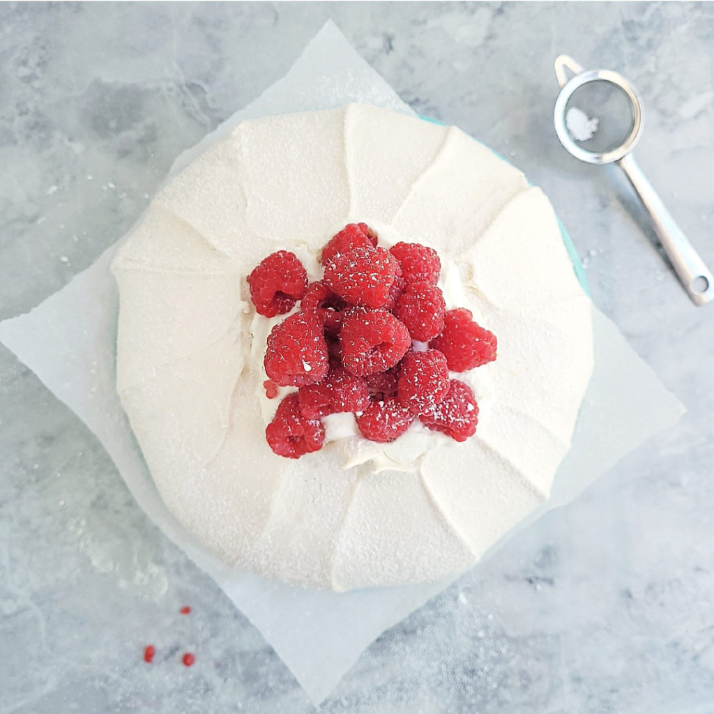 functional image pavlova with red raspberries top down view dusted with powdered sugar on a gray marble surface