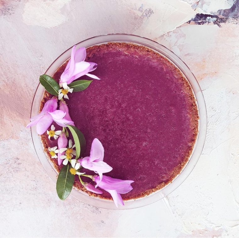 functional image purple sweet potato pie decorated with purple flowers uncut in a clear pie dish on an abstract background