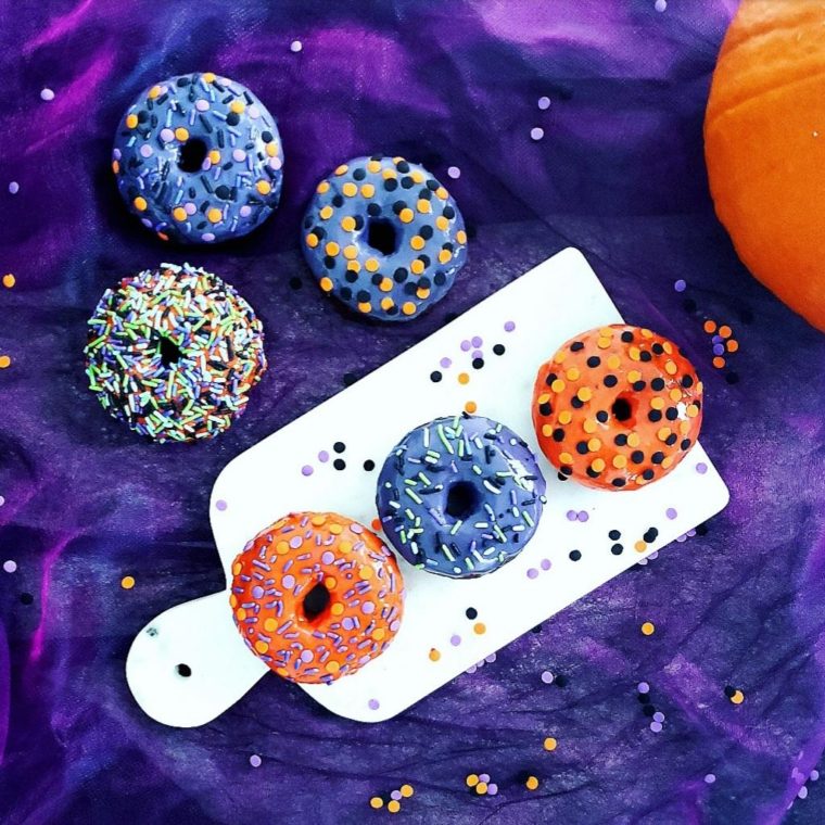 functional image halloween donuts with sprinkles top down view on purple tulle background baked halloween donuts with orange and purple icing and festive sprinkles