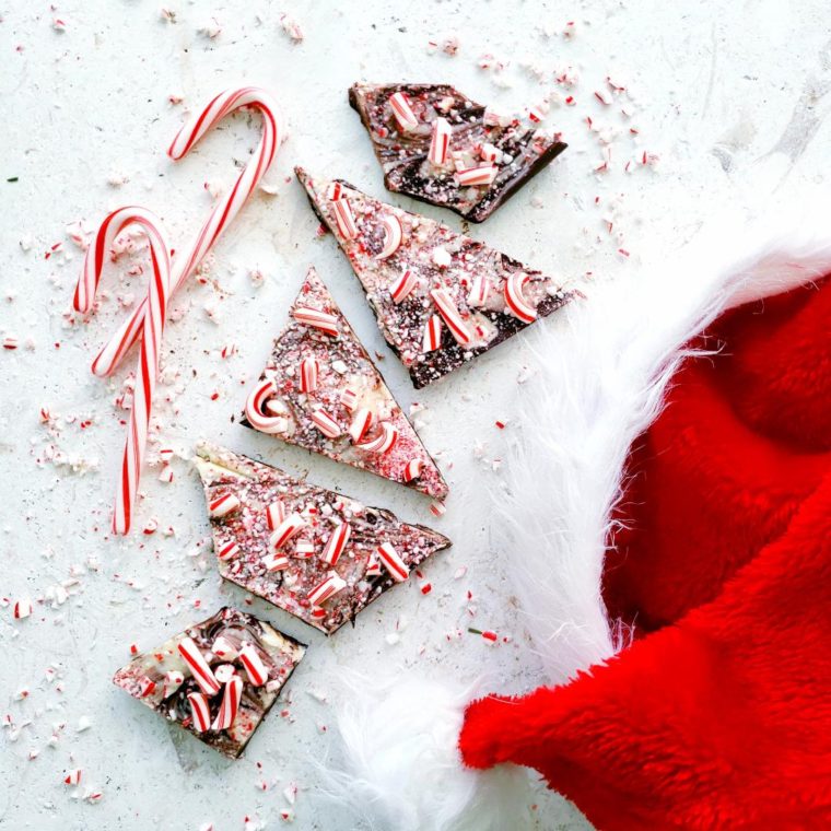 boozy peppermint bark top down four irregular shaped pieces with crushed candy canes on top styled with a santa hat