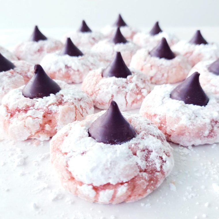 pink velvet blossom cookies with dark chocolate hershey kissed and powdered sugar on the pink cookies to look like snow