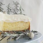 white chocolate christmas cheesecake with white chocolate whipped cream side view of sliced cake to showcase layers