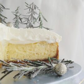 white chocolate christmas cheesecake with white chocolate whipped cream side view of sliced cake to showcase layers