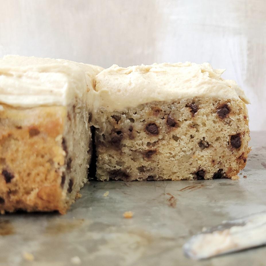 banana chocolate chip sheet cake with peanut butter cream cheese frosting close up side view of sheet cake with one slice missing so you can see the moist inner crumb and chocolate chips