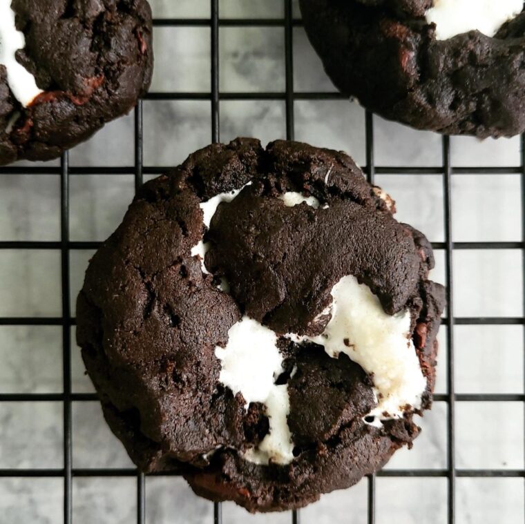 chocolate marshmallow cookies stuffed cookies black cocoa cookie top down view on a black baking rack to see the black and white swirls of chocolate and marshmallow