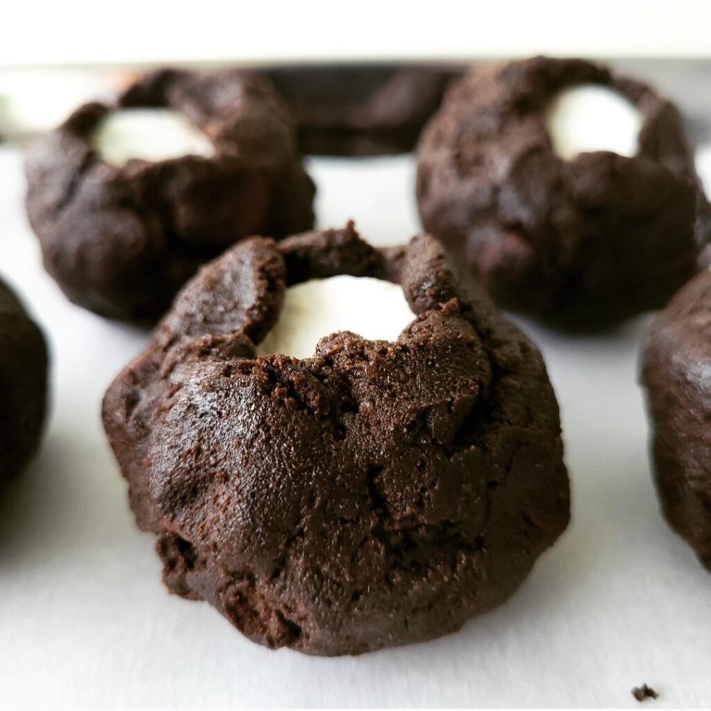 chocolate marshmallow cookies close up view of unbaked cookie dough balls. stuffed cookies are chocolate dough wrapped around jumbo marshmallows