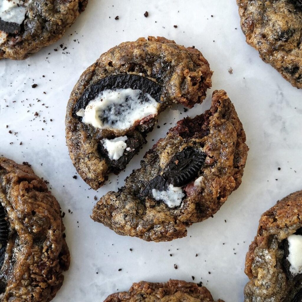 oreo chocolate chip cookies top down view of a cookie broken in half surrounded by crumbs and on a gray marble surface