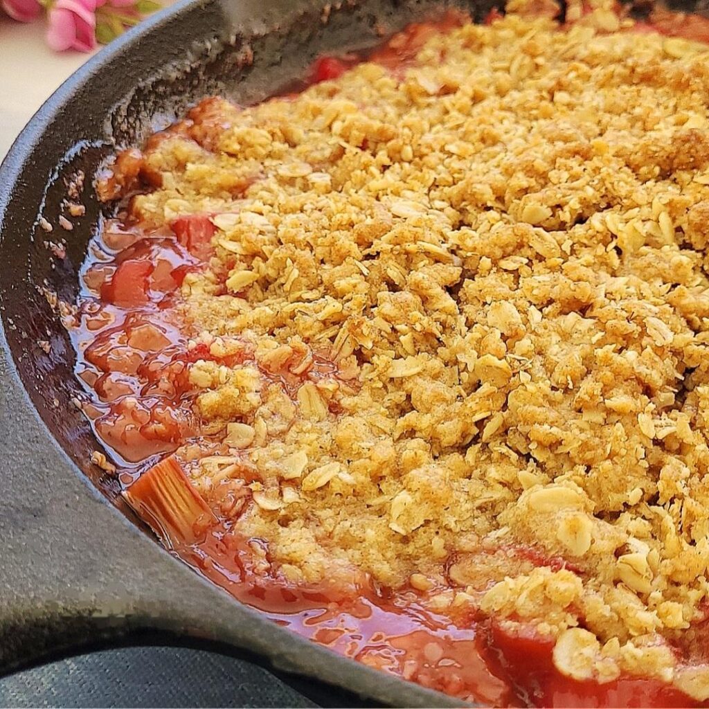 rhubarb crisp in a cast iron skillet close up view of oat crisp and rhubarb fruit filling 