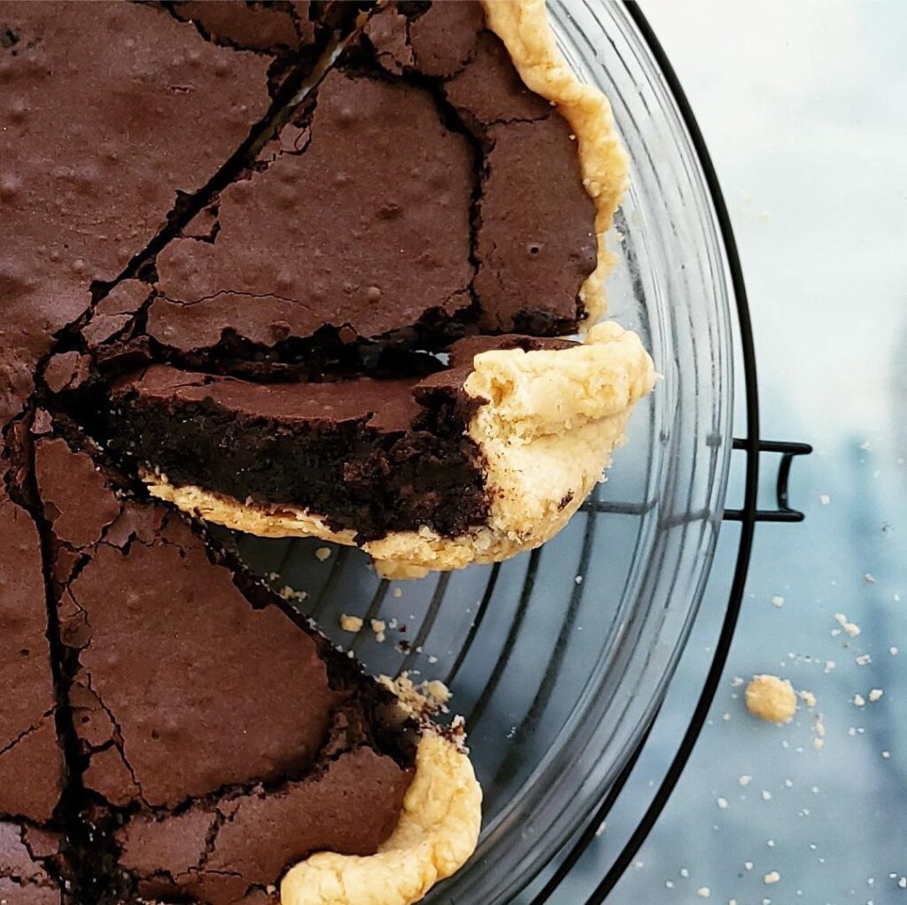 dark chocolate chess pie top down close up view of cut pie with one slice turned on its side so you can see the fudgy interior layer.