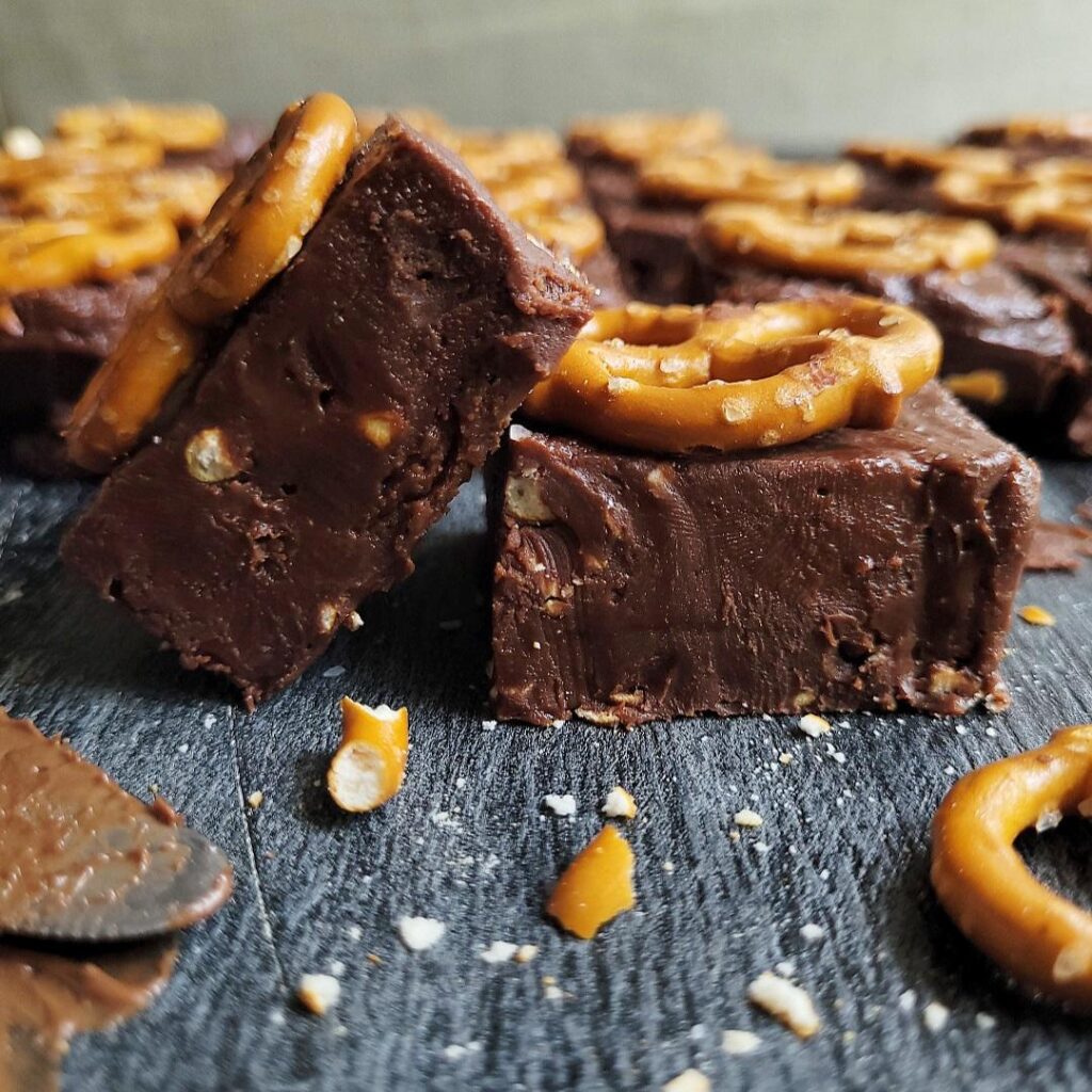 no bake nutella fudge with salted pretzels on top. fudge is cut into squares and one square is leaning on another. close up side view. 