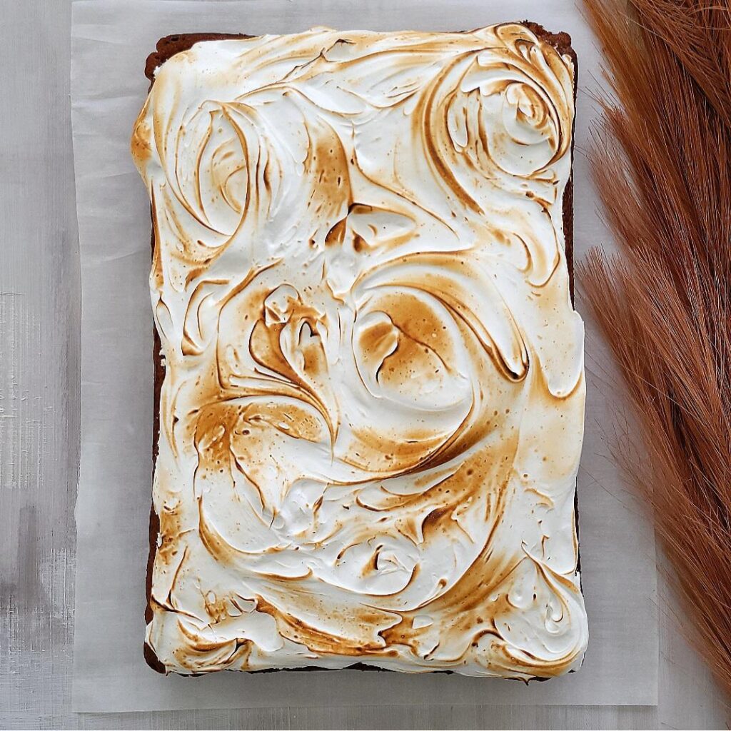 sweet potato sheet cake with marshmallow meringue frosting. top down view of uncut cake. frosting has been toasted with a blow torch. 