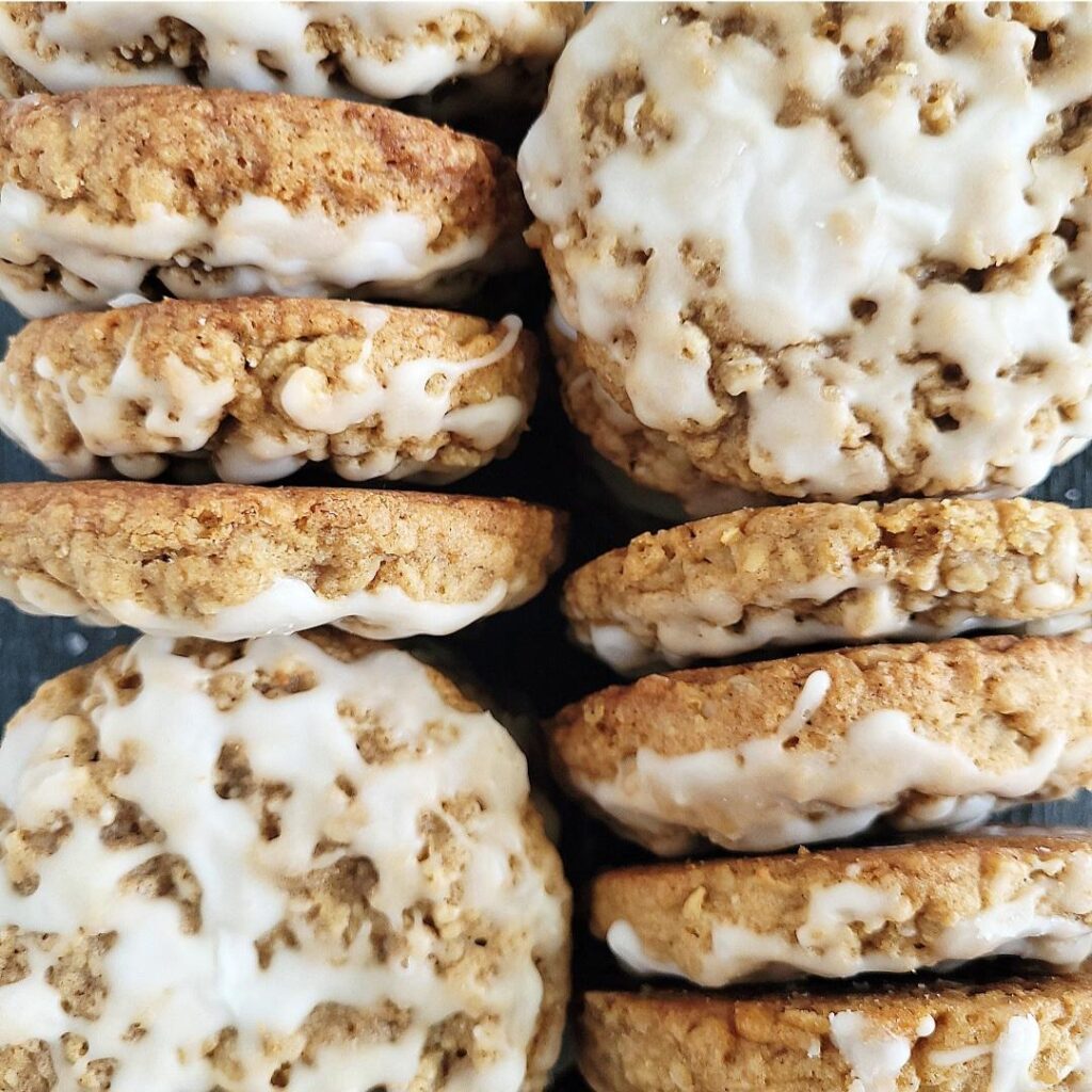 old fashioned iced oatmeal cookies. close up of cookies with vanilla glaze. top down view. there is a mix of cookies standing on their sides and cookies laying flat so you can see all angles. 