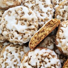 old fashioned iced oatmeal cookies. pile of cookies with white icing. one cookie has been cut in half and is turned on its side facing up so you can see the inner crumb.