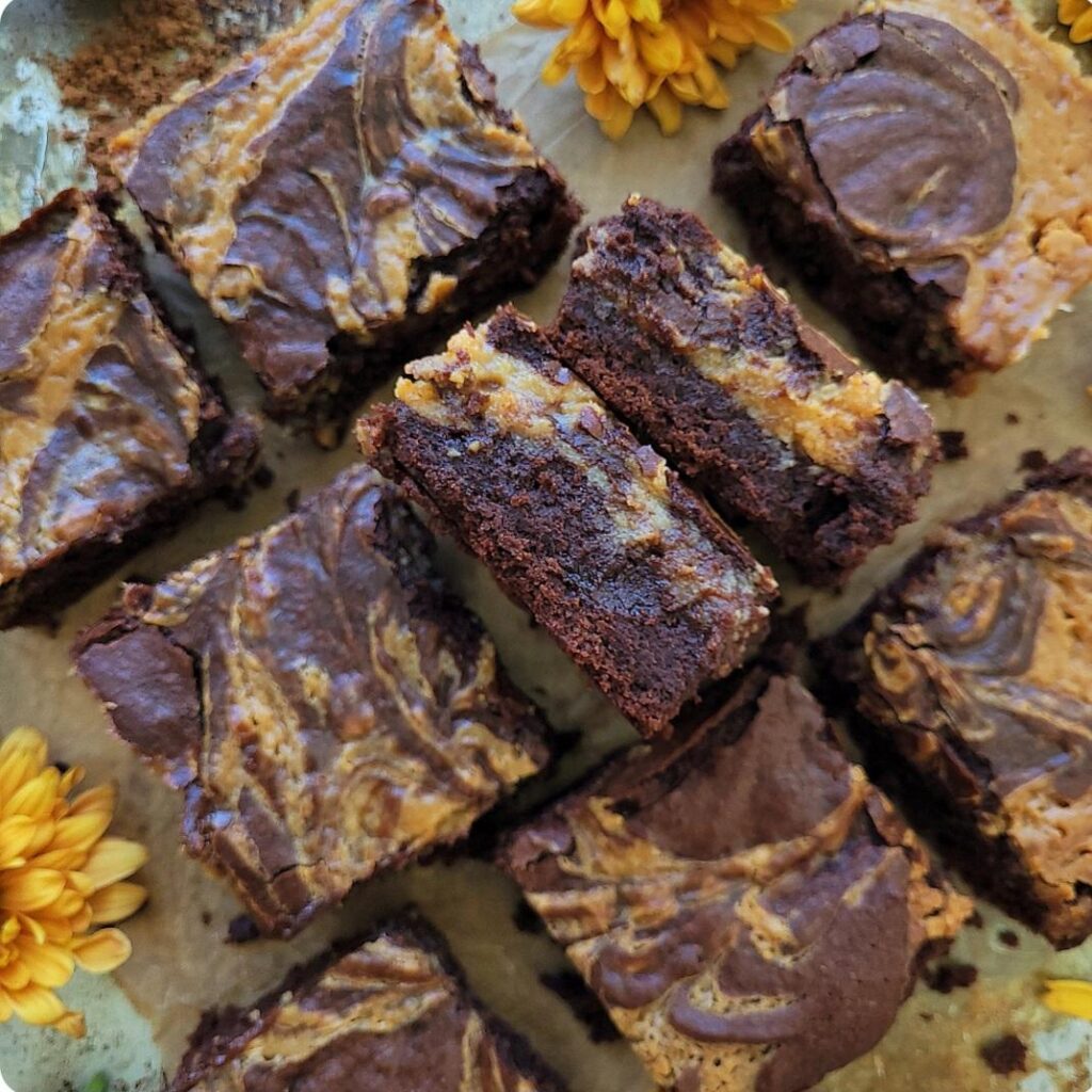 caramel brownies. top down view of brownies cut into squares. two brownie slices are on their sides so you can see the inner layer. 