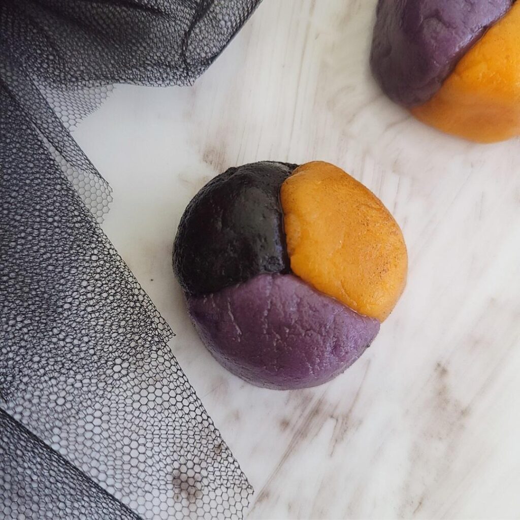 hocus pocus cookies. close of view of tri-colored cookie dough all before baking. cookie ball contains 1/3 orange dough, 1/3 black dough and 1/3 purple dough for the perfect halloween cookie. 