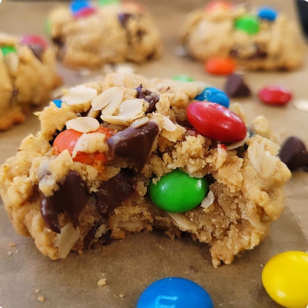 easy monster cookies. close up view of M&M monster cookie bitten so you can see the inner chocolate chips, colorful M&M's and coats. 