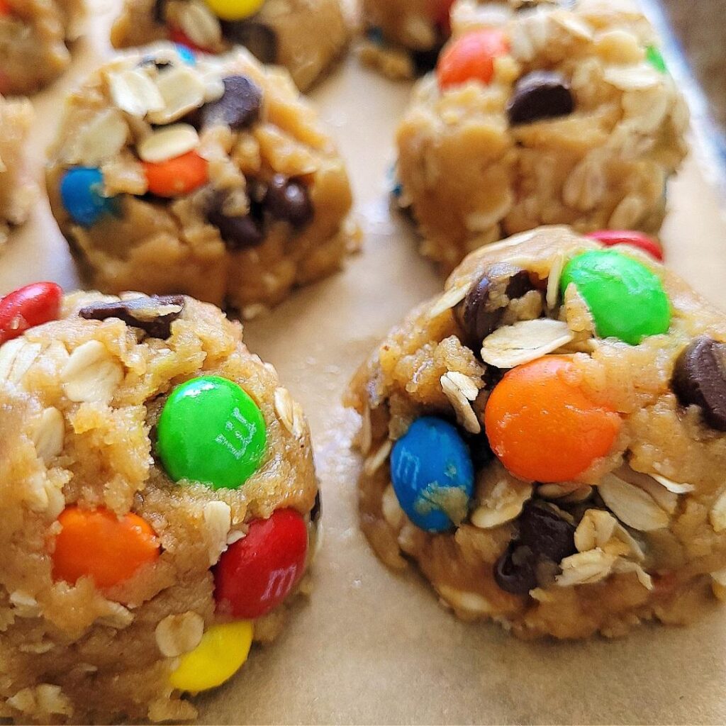 easy monster cookies. cookie dough balls ready to bake with oats, chocolate chips and colorful m&m's