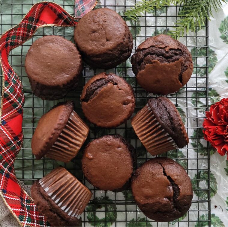 chocolate gingerbread muffins. top down view of muffs on a baking rack styled with christmas ribbon.