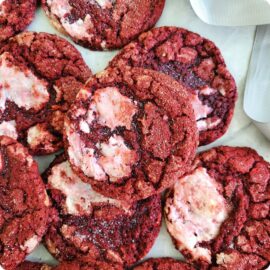 flat pile of crackly red velvet cookies with patches of cream cheese baked into the dough.