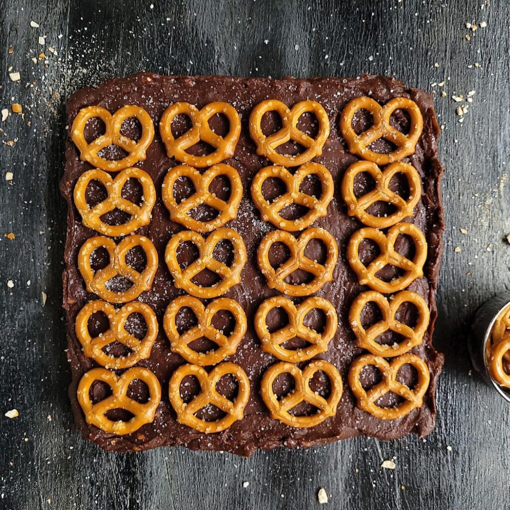 salted pretzel nutella fudge. top down view of the uncut block of chocolate fudge topped with rows of mini pretzels. 