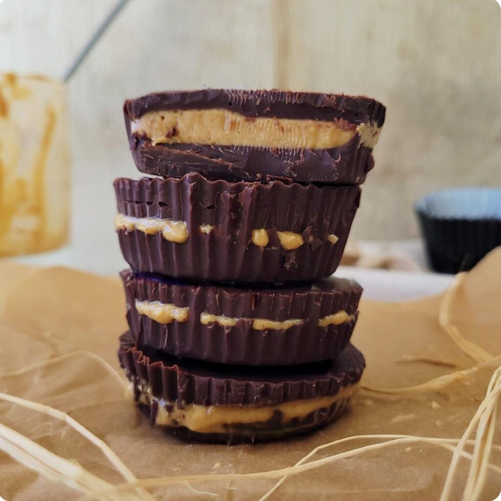 dark chocolate peanut butter cups. stack of 4 homemade peanut butter cups. top peanut butter cup is cut in half so you can see the creamy peanut butter inside. 