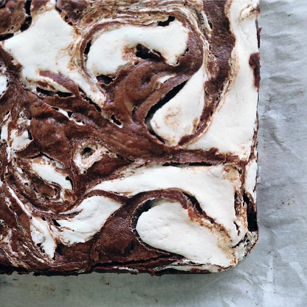 top down, zoomed in view of the corner of a pan of chocolate brownies swirled with marshmallow. 