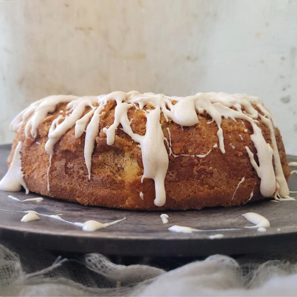 cinnamon bundt cake. side view of bundt cake with cinnamon cream cheese glaze dripping down the sides.
