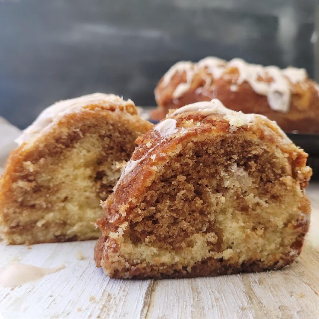 cinnamon bundt cake with cinnamon cream cheese glaze. side view of two slices so you can see the cinnamon swirl inside the cake. 