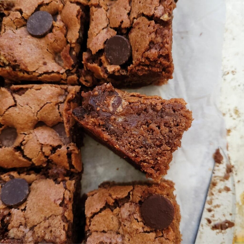 chocolate banana brownies. top down view of cut brownies with one brownie square turned on its side so you can see the inner crumb. 