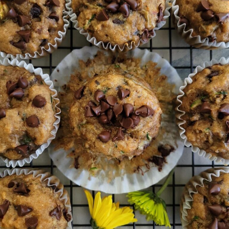 banana zucchini muffins with chocolate chips. top down view of muffins on a wire baking rack and yellow and green flowers